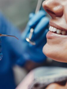 a woman smiling and getting check up done by a dentist.