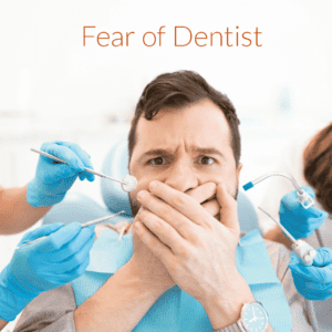 An image of a patient covering  his mouth with both hands due to dental fear and anxiety.Dentists hands with Dental instruments can be seen on the side.